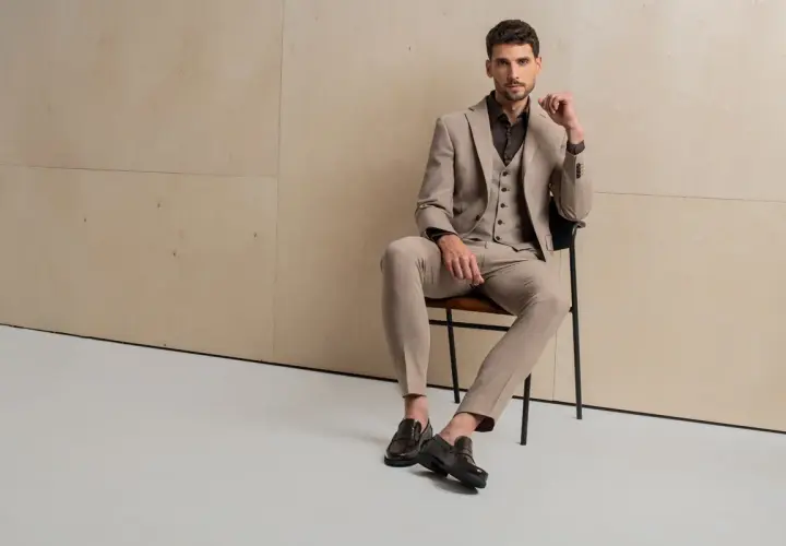 Elegancki mężczyzna w garniturze i kamizelce prezentuje, co to za buty: stylowe, ciemne loafersy.