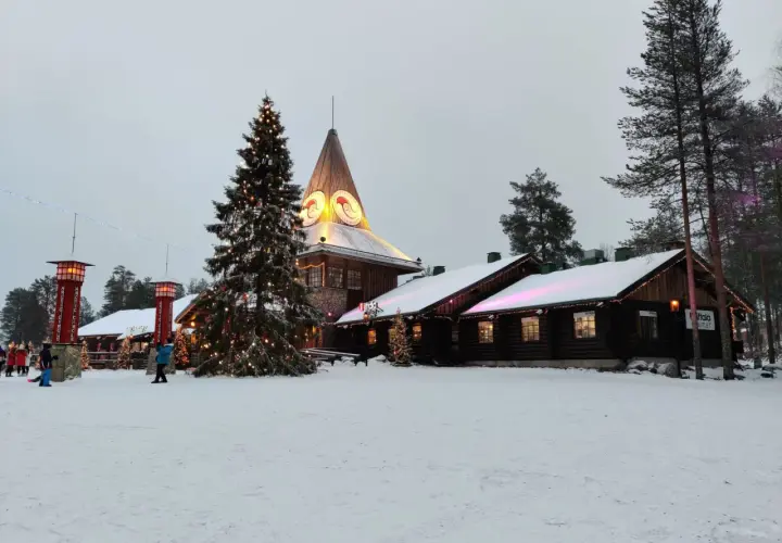 Śnieżny krajobraz z choinką i budynkami, gdzie znajduje się dom Świętego Mikołaja.