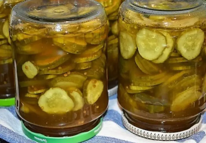 Słoiki pełne plasterków ogórków w zalewie z przyprawami, gotowe do podania jako dodatek do dań. Te ogórki w curry z pewnością dodadzą smaku!