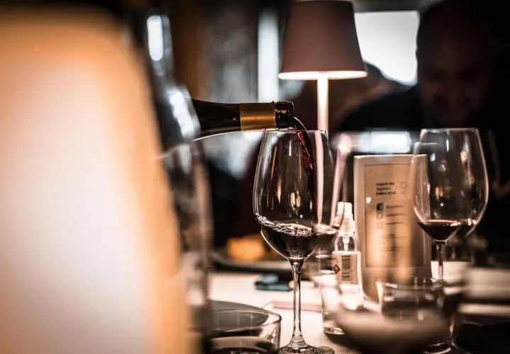 Verre de vin rouge servi dans un bar, ambiance feutrée.
