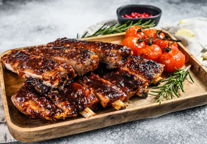 Soczyste żeberka w sosie BBQ, podane z pieczonymi pomidorkami i rozmarynem. Idealne na obiad lub grilla.