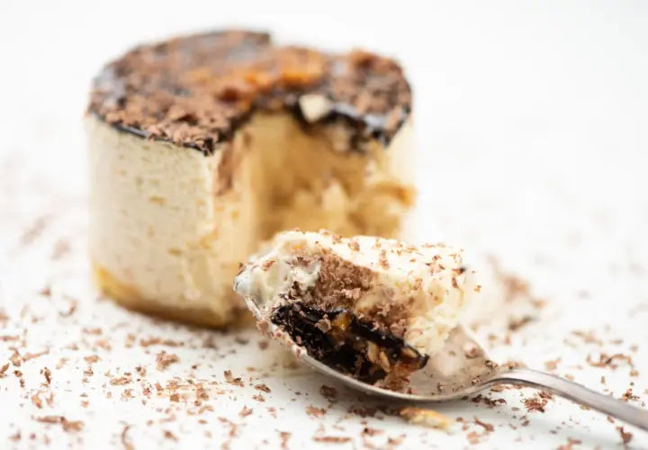 Un cucchiaino raccoglie un pezzo di delizioso parfait, con strati di crema e cioccolato, cos'è questa bontà?