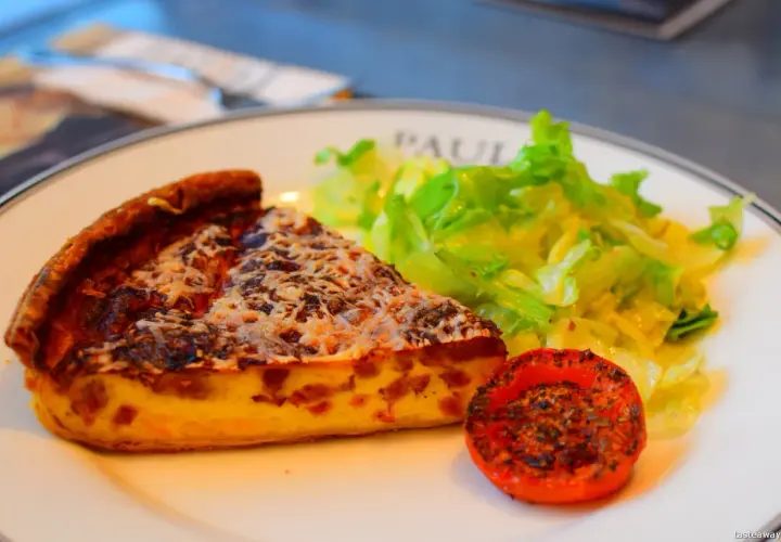 Kawałek quiche lorraine, sałatka i pieczony pomidor – klasyka kuchni francuskiej.