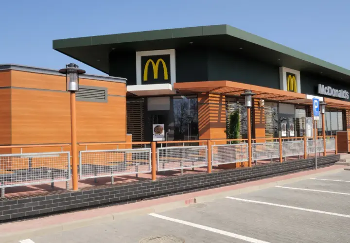 Nowoczesny McDonald's z drewnianymi elementami i dużymi oknami. Idealne miejsce na szybki posiłek, może nawet na słynne krewetki McDonald's, jeśli będą dostępne.