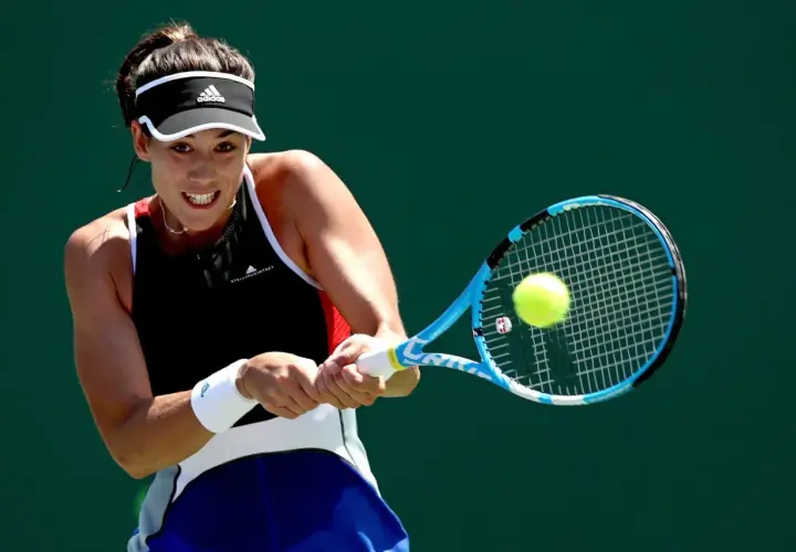 Garbine Muguruza z determinacją uderza piłkę rakietą podczas meczu tenisowego.