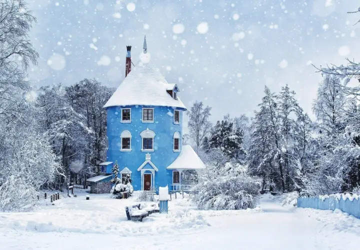 Niebieski domek w śnieżnym lesie, jak z bajki. To prawdziwy winter wonderland tekst, otoczony drzewami pokrytymi białym puchem.