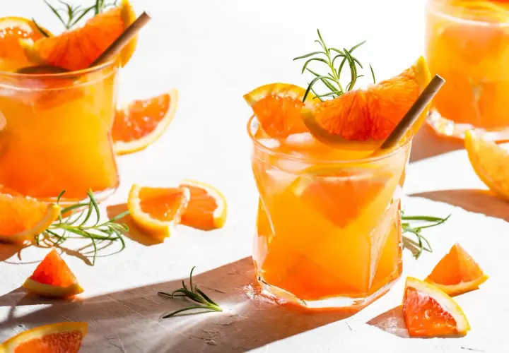 Erfrischender Aperitif mit Prosecco, Orangenstücken und Rosmarin. Perfekt für einen sonnigen Nachmittag.