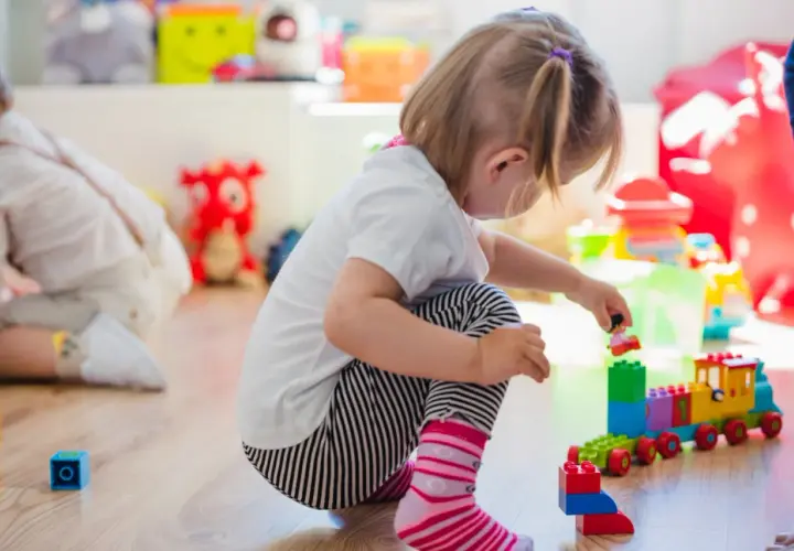 Niña jugando con bloques, concentrada en su mundo, un ejemplo de egocentrismo infantil.