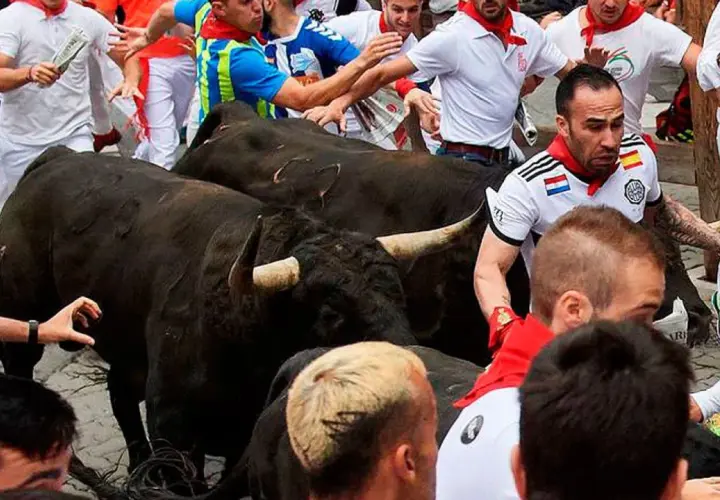 Hombres corren junto a toros negros de ganadería Guadaira.