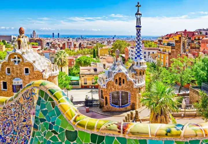 Kolorowa mozaika i budynki w Parku Güell w Barcelonie z widokiem na miasto.