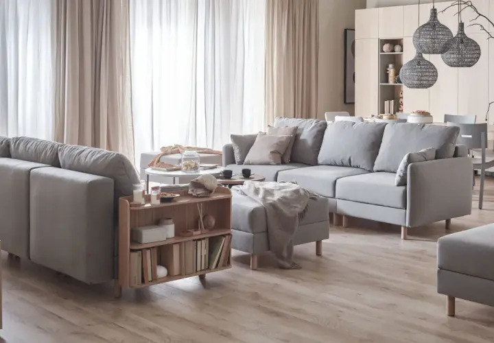 Przytulny salon inspiracje: szara sofa, drewniane meble, jasne zasłony i dekoracje tworzą ciepłą atmosferę.