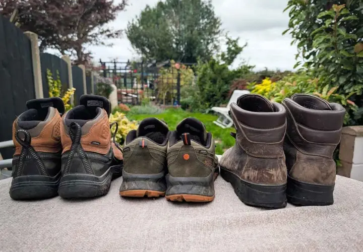 Choosing hiking boots: A selection of hiking boots and shoes, from lighter trail runners to sturdy leather boots, are lined up outdoors.
