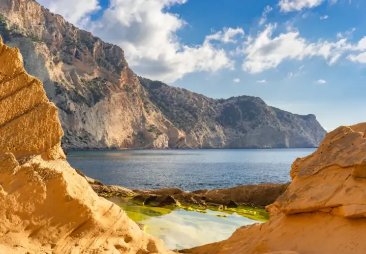 Acantilados dorados y mar azul en Ibiza, un rincón que evoca la magia de Atlantis Ibiza.