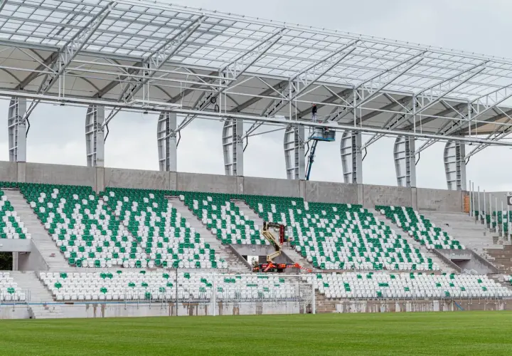 Stadion Radomiaka w budowie. Zielono-białe trybuny czekają na kibiców, a pracownicy montują dach.