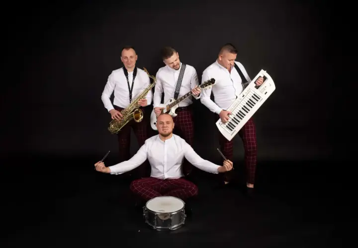 Zespół muzyczny grupa speed: saksofonista, gitarzysta, klawiszowiec i perkusista w białych koszulach i bordowych spodniach w kratę.