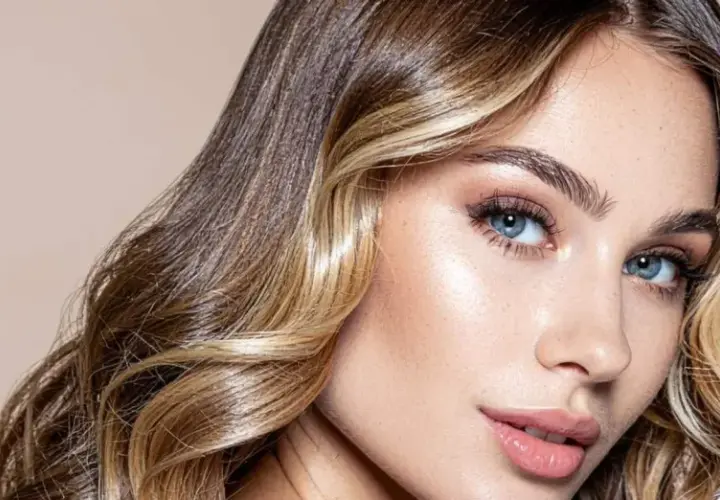 Mujer con cabello castaño y rubio, con un "money piece" que ilumina su rostro. Sus ojos azules y labios rosados resaltan su belleza.