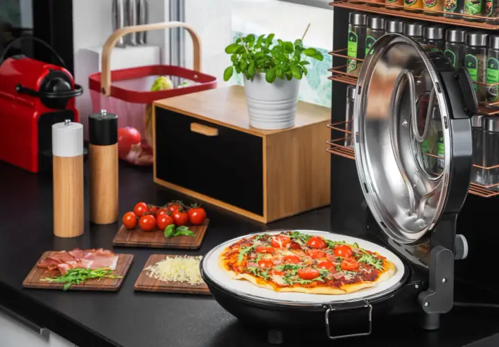 Gotowa pizza na kamieniu w otwartym piecyku, obok składniki: pomidorki, rukola, szynka, ser.