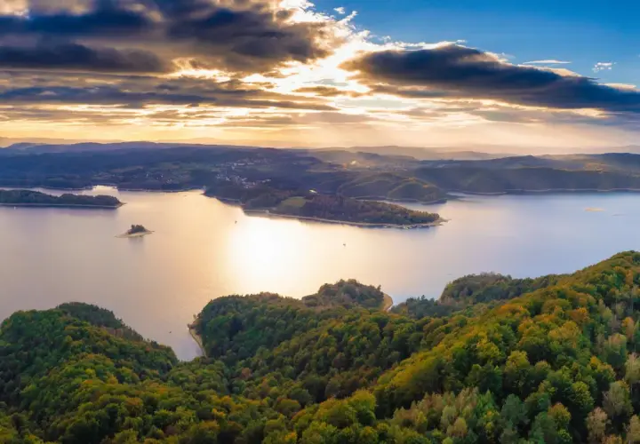 Zachód słońca nad jeziorem Solina. Widać zalesione wzgórza, wyspy i zatoczki. Idealne miejsce na odkrywanie atrakcji Solina i okolice.