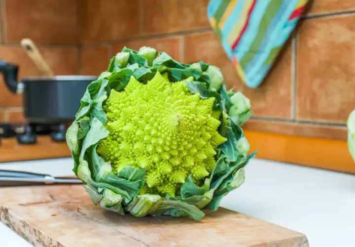 Zielony brokuł romanesco o spiralnym kształcie, gotowy do przygotowania na desce do krojenia w kuchni.