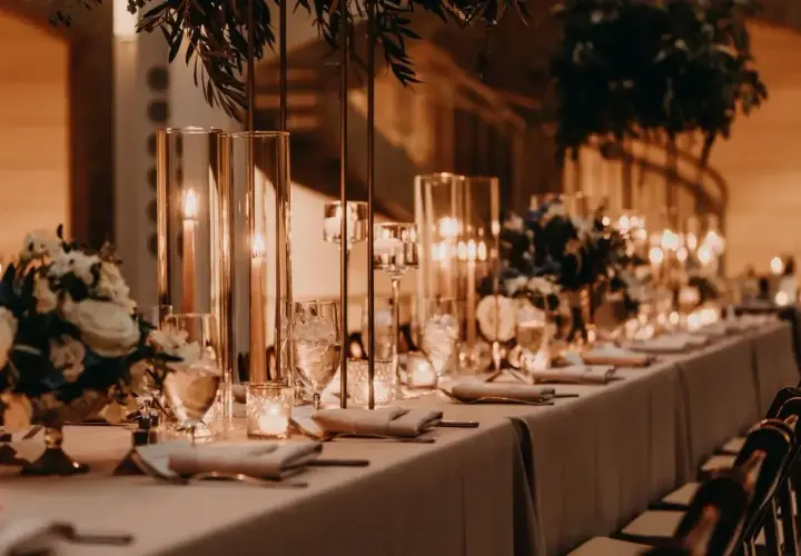 Elegancka sala weselna z długim stołem, świecami i kwiatami. Zastanawiasz się, ile kosztuje sala weselna?