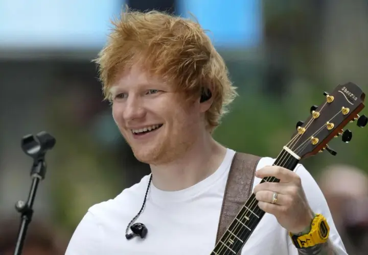Ed Sheeran uśmiecha się, grając na gitarze podczas koncertu w Polsce.