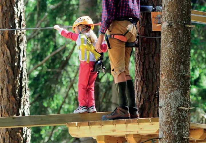 Un bambino e un adulto su un percorso avventura. Un perfetto weekend con bambini nel Nord Italia, tra alberi e adrenalina.