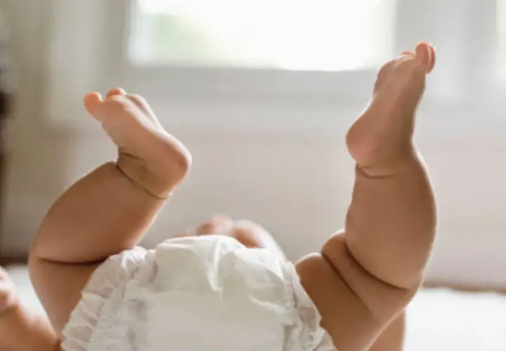 Gambe paffute di un neonato con pannolino, un tenero culo rosso pronto per un cambio.