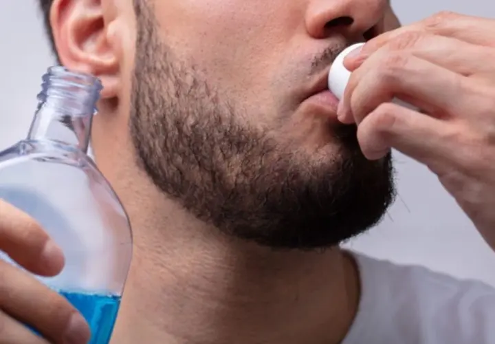 Uomo usa collutorio per parodontite, tenendo una bottiglia di liquido blu.