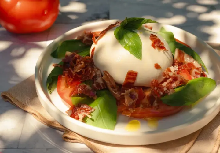 Deliciosa ensalada de burrata con tomates, albahaca fresca y crujiente jamón serrano.