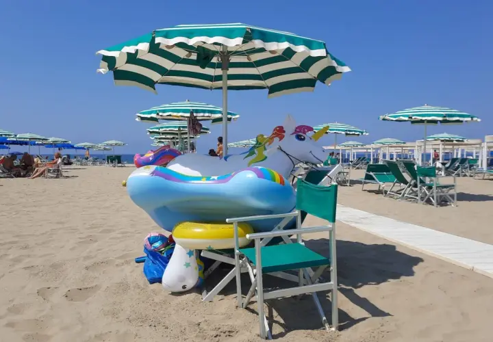 Spiaggia di Viareggio con gonfiabili a forma di unicorno e arcobaleno, pronti per i bambini.