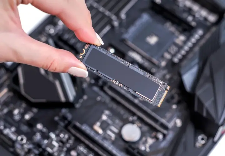 Eine Hand hält eine M.2 SSD über einem Motherboard, bereit für den Einbau. Ein M.2 SSD Test steht an.