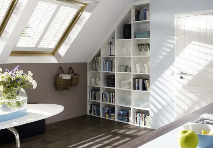 Una libreria in mansarda, piena di libri e oggetti decorativi, si integra perfettamente con l'ambiente.