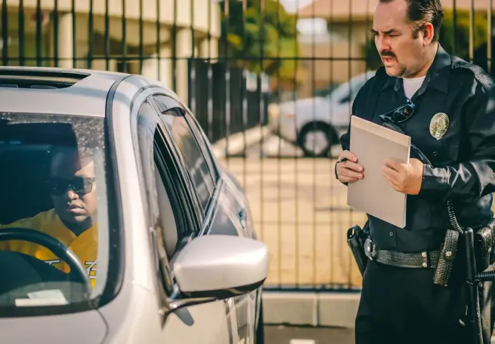 Policjant wręcza kierowcy mandat za spowodowanie kolizji.