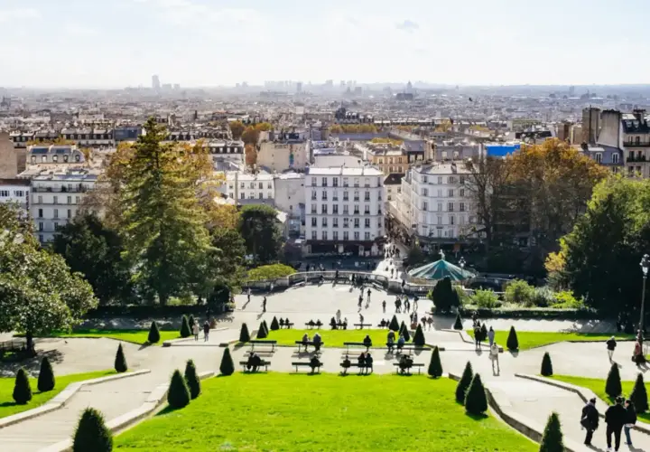Blick über das Montmartre Viertel in Paris. Menschen genießen den sonnigen Tag im Park mit Blick auf die Stadt.