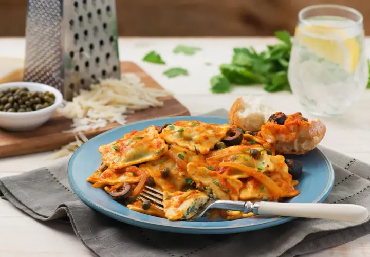Délicieux ravioli ricotta épinard, une recette italienne savoureuse, servie avec une sauce tomate, des olives et des câpres.