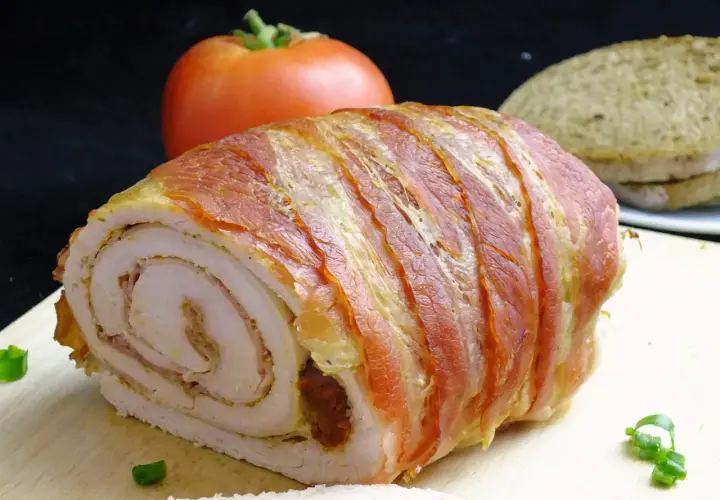 Roladki z indyka z boczkiem, soczyste i aromatyczne, gotowe do podania z pomidorem i chlebem.