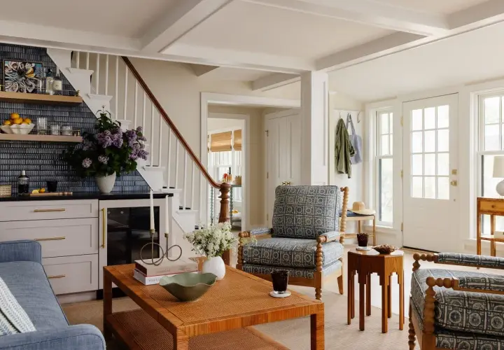 A living room showcasing diverse furniture styles, from a blue sofa and patterned armchairs to a rattan coffee table and a wooden side table.