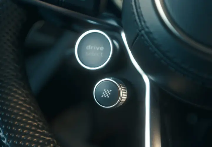 Przycisk z szachownicą na kierownicy, gotowy do aktywacji launch control. Obok przycisk Drive Select.