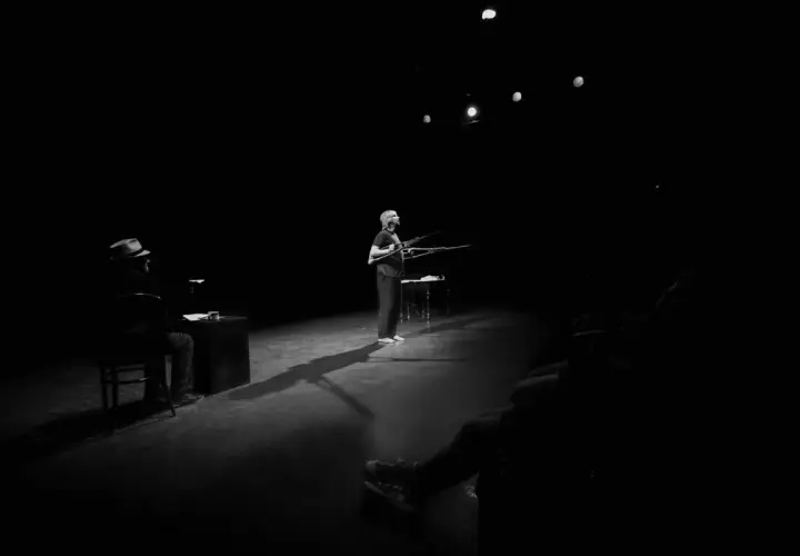 Na scenie Teatru Rondo w Słupsku kobieta z karabinami, mężczyzna w kapeluszu siedzi przy biurku.