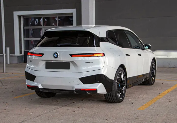 Białe BMW iX z czarnymi akcentami stoi na parkingu.
