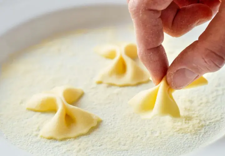 Hand formt Farfalle-Nudeln in einer Schüssel mit feiner farina di semola.