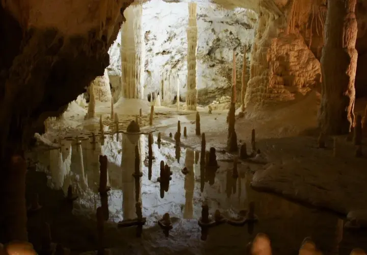 Stalattiti e stalagmiti riflettono in uno specchio d'acqua nelle grotte di Frasassi, dove si trovano meraviglie naturali.