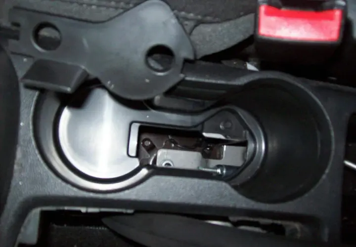 Detailaufnahme des Innenraums eines Opel Mokka, Fokus auf den Bereich um den Getränkehalter, wo das Handbremsseil gewechselt wird.