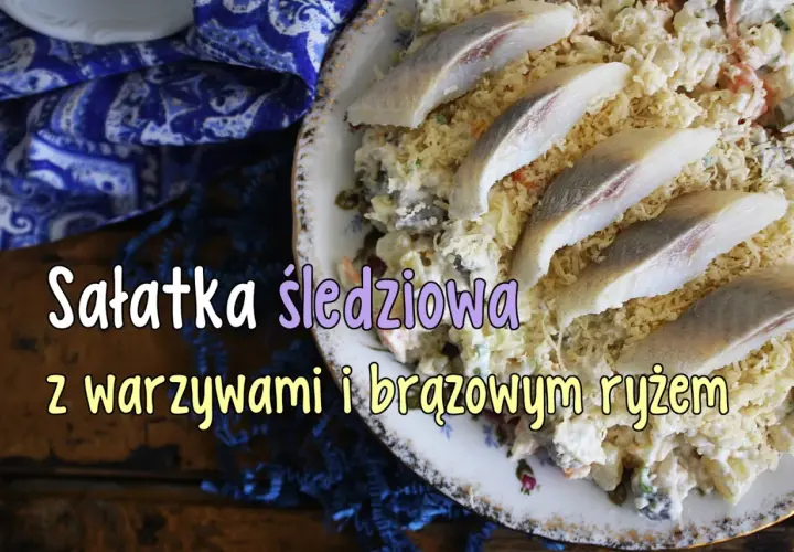 Sałatka śledziowa z warzywami i brązowym ryżem, ozdobiona kawałkami marynowanych śledzi.