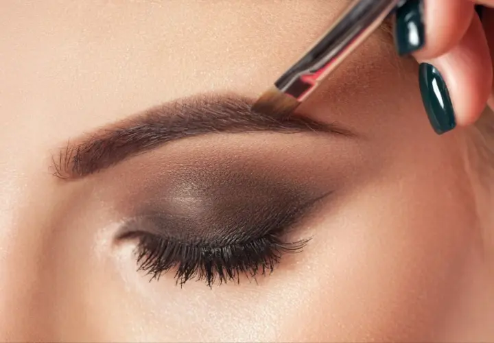 Aplicando el toque final al maquillaje de cejas con un pincel.