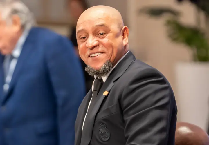 Roberto Carlos żyje i uśmiecha się szeroko, ubrany w elegancki garnitur z herbem Realu Madryt.