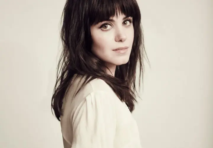 Katie Melua, jakby śpiewała "I Will Be There", z ciemnymi włosami i przenikliwym spojrzeniem.