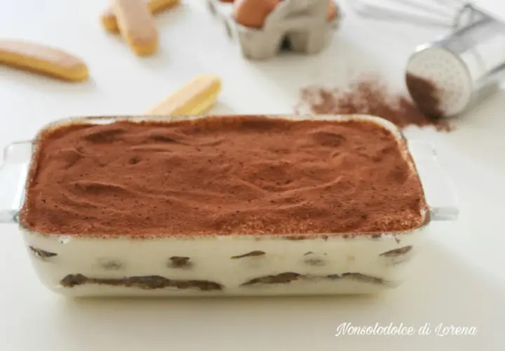 Tiramisù pronto in teglia, con strati di savoiardi e crema al mascarpone, spolverato di cacao. La ricetta perfetta per un dolce goloso.