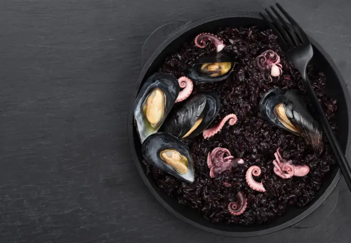 Arroz negro con mejillones y pulpo tierno, un plato de mariscos oscuro y delicioso.