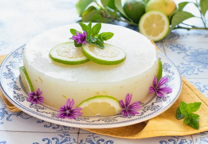 Delizioso gelo di limone, decorato con fette di limone, fiori viola e foglie di menta. Fresco e invitante.